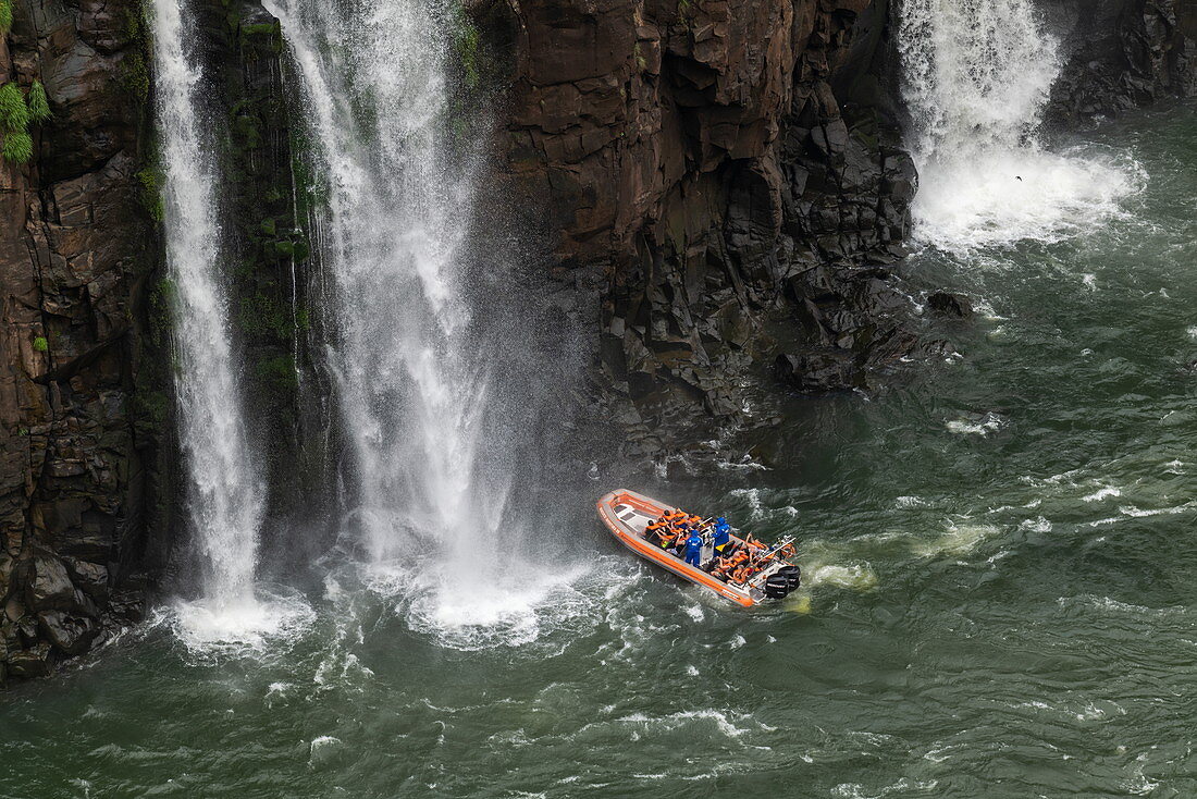 Blick auf Jetboot das sich einem Wasserfall der Iguazu Falls nähert, Iguazu National Park, Parana, Brasilien, Südamerika