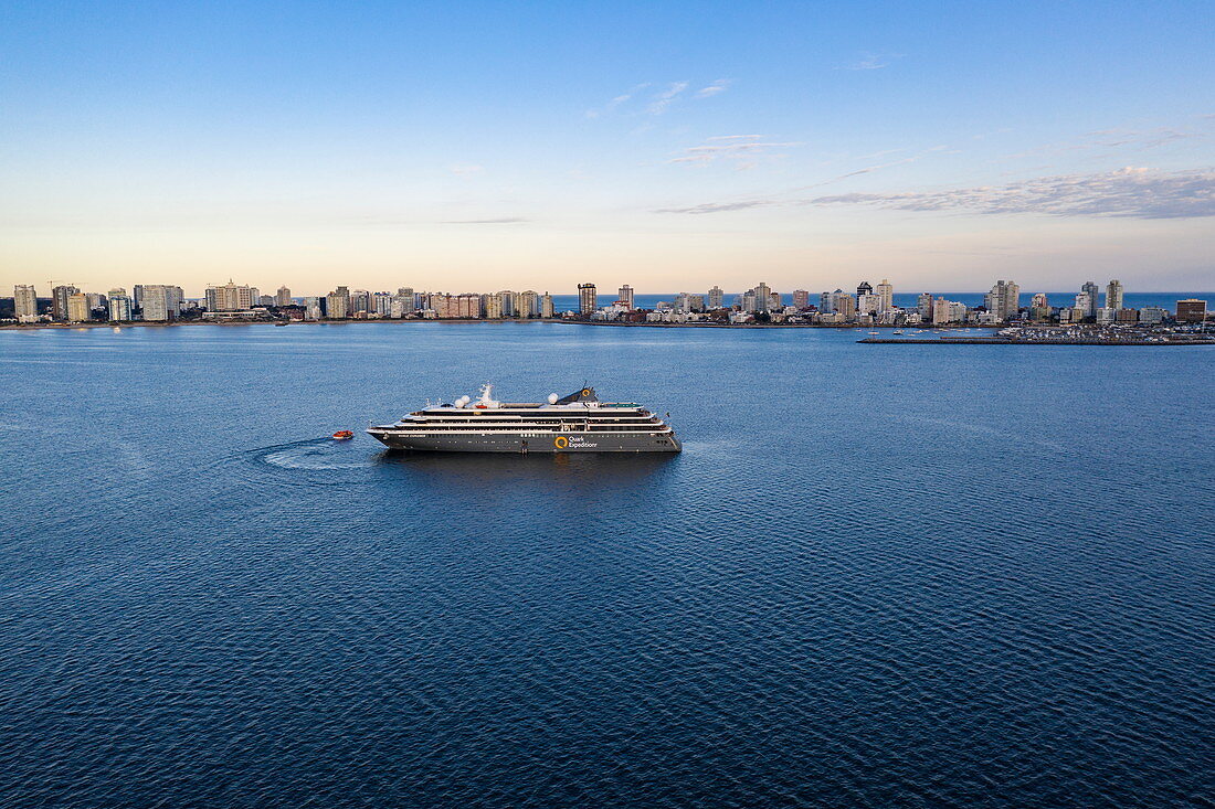 Luftaufnahme von Expeditions Kreuzfahrtschiff World Explorer (nicko cruises) mit Skyline der Stadt dahinter bei Sonnenuntergang, Punta del Este, Maldonado Department, Uruguay, Südamerika