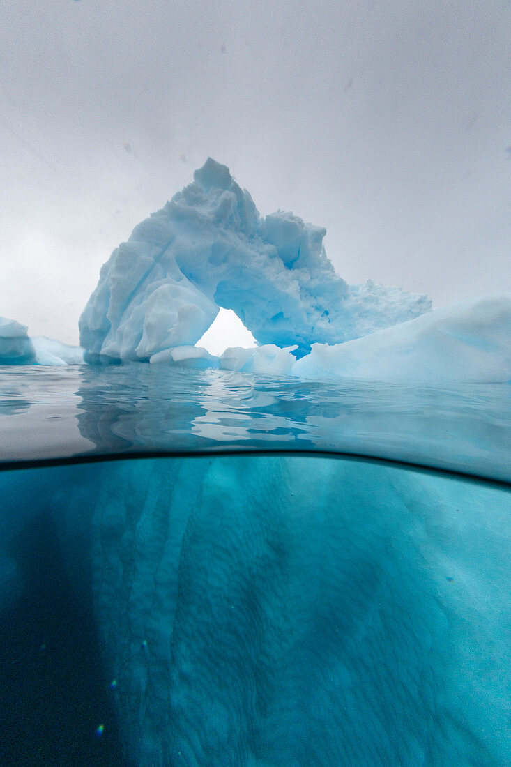 Ober- und Unteransicht eines Bogens, der in einem Eisberg auf Cuverville Island, Ererra-Kanal, Antarktis, Polarregionen gebildet wurde