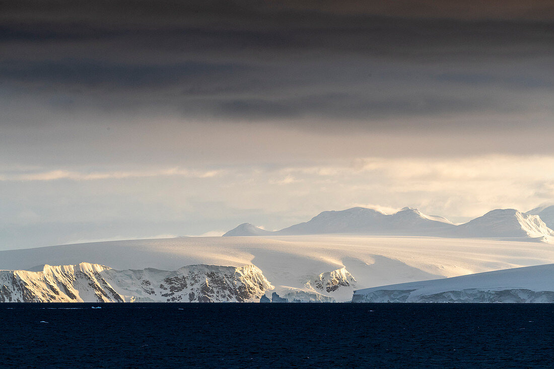 Sonnenaufgang auf schneebedeckten Bergen und Gezeitengletschern im Hafen von Mikkelsen, Trinity Island, Antarktis, Polarregionen