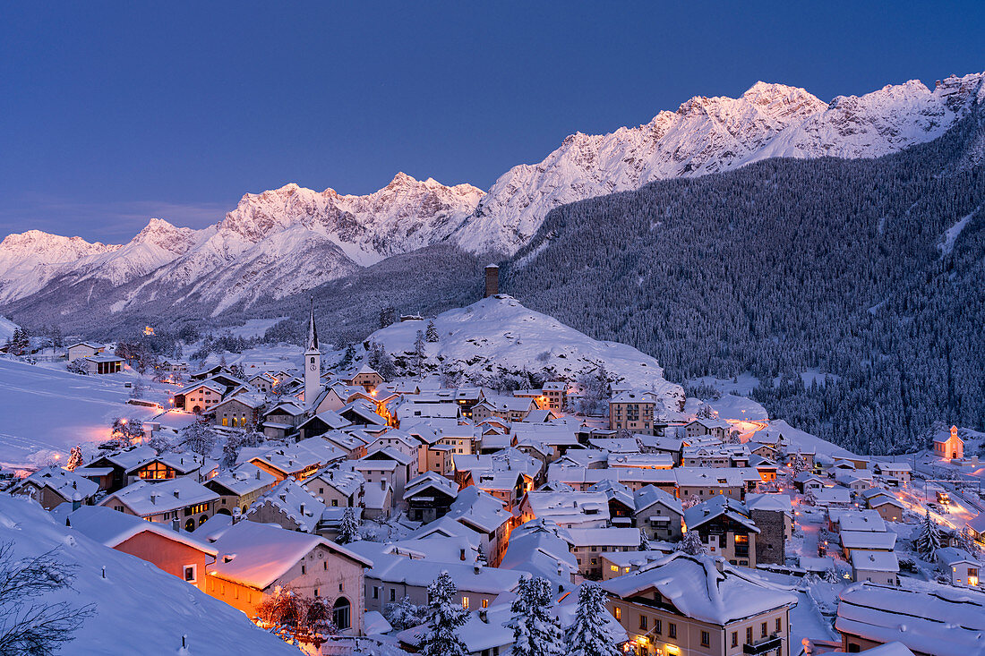 Traditionelle Häuser bedeckt mit Schnee während der Winterdämmerung, Ardez, Engadin, Kanton Graubunden, Schweiz, Europa