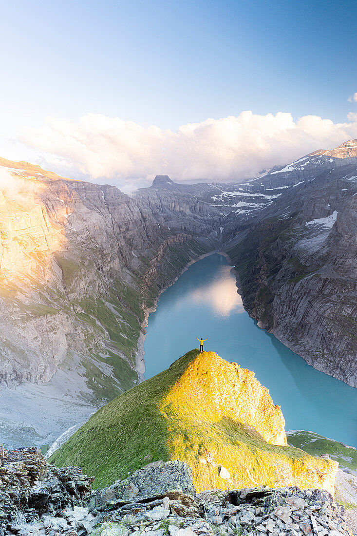 Luftaufnahme des fröhlichen Mannes mit ausgestreckten Armen, die See Limmernsee bei Sonnenuntergang, Kanton Glarus, Schweiz, Europa bewundern