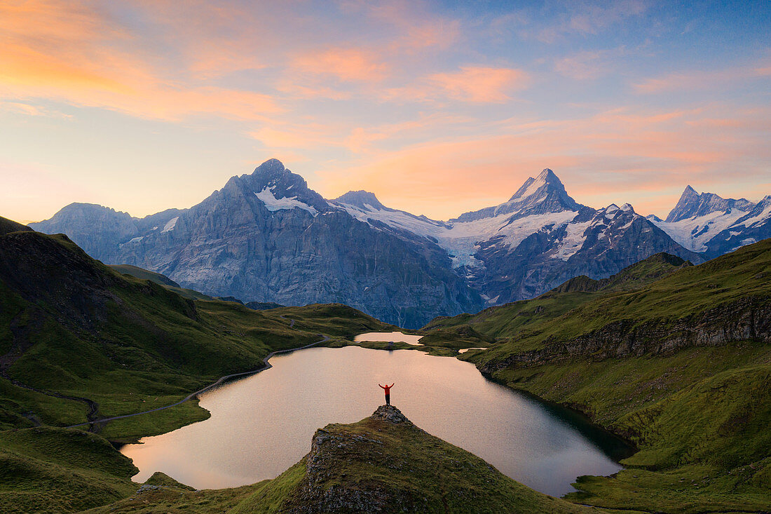 Fröhlicher Wanderer, der Wetterhorn, Schreckhorn und Finsteraarhorn vom Bachalpsee im Morgengrauen, Berner Oberland, Schweiz, Europa bewundert