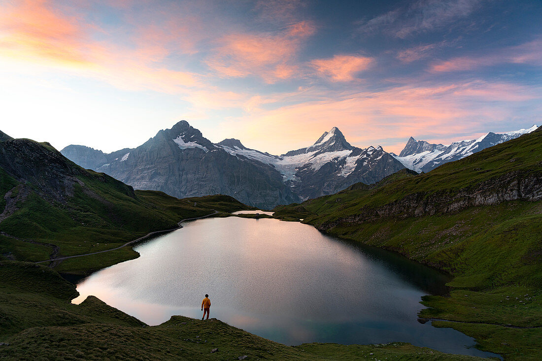 Hiker admiring sunrise from the shores of Bachalpsee lake, Grindelwald, Bernese Oberland, Bern Canton, Switzerland, Europe