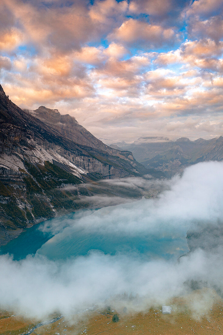 Wolken bei Sonnenuntergang über dem unberührten Oeschinensee im Nebel, Berner Oberland, Kandersteg, Kanton Bern, Schweiz, Europa