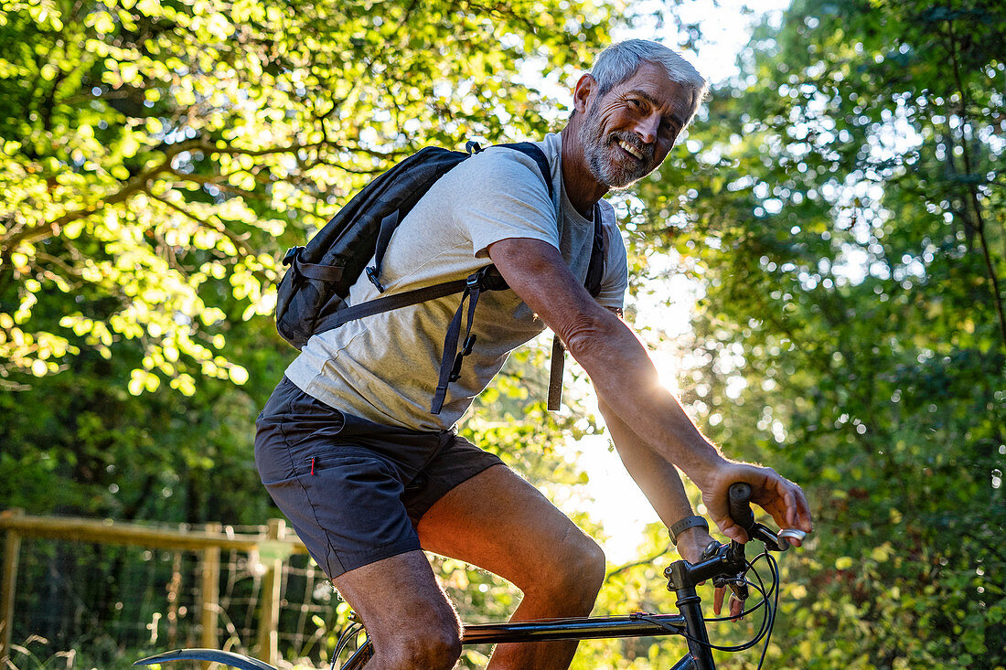 Portrait of smiling mature man cycling in forest