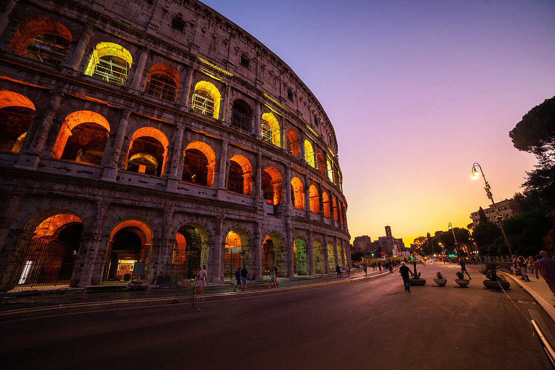 Low angle view of tourists walking on street outside Colosseum at dusk,Rome