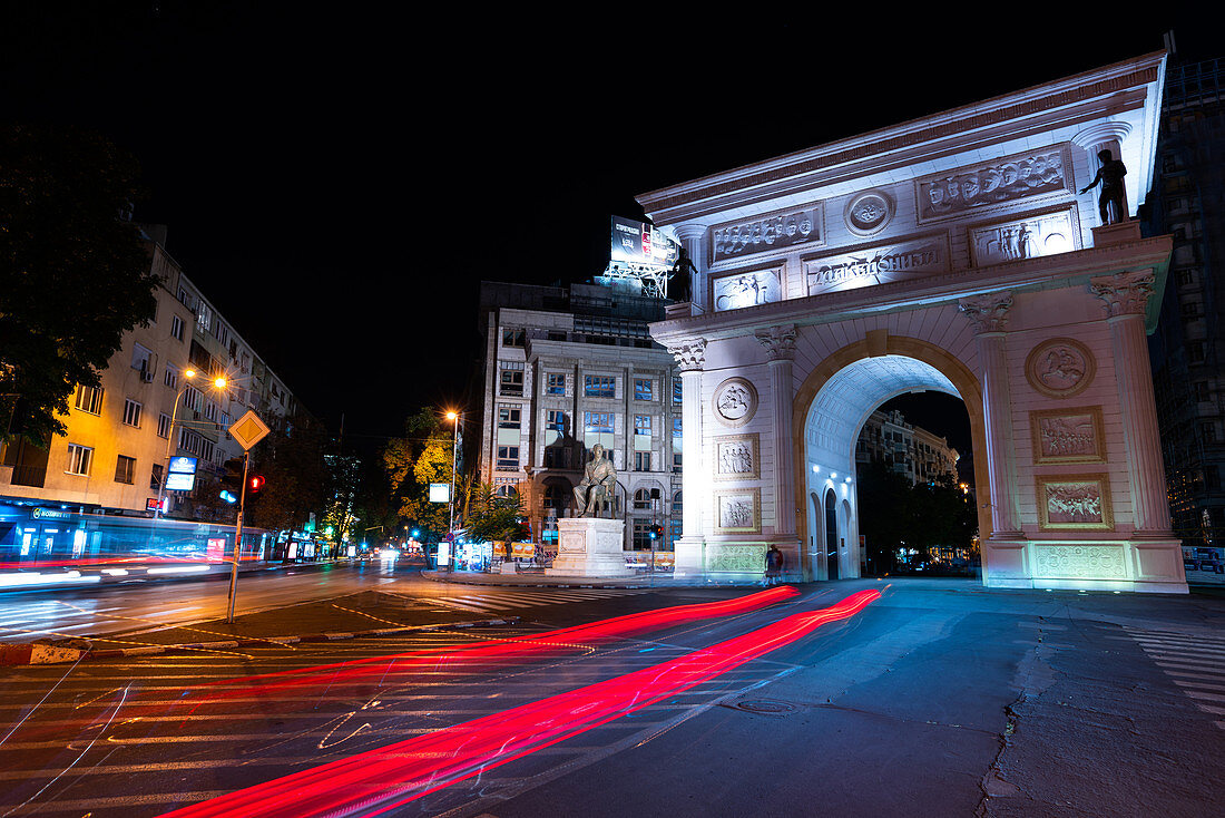 Macedonia Gate with light trail of traffic driving on street in foreground,Skopje city