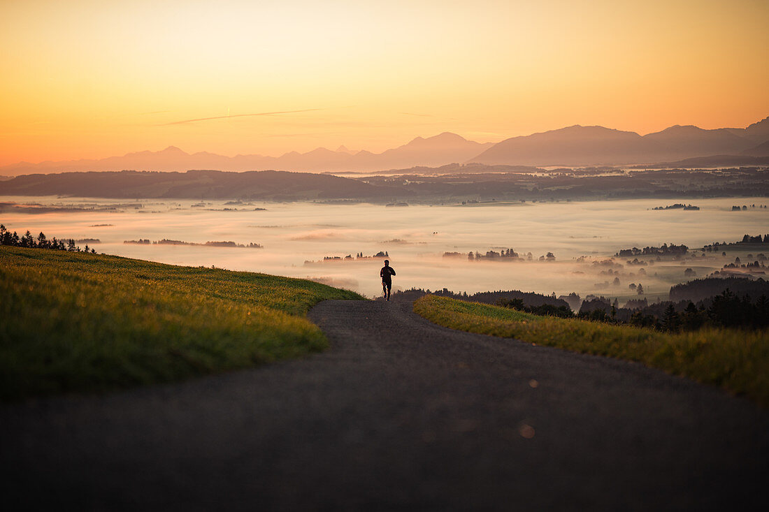 Läufer auf einem leeren Weg in den Morgenstunden, Allgäu