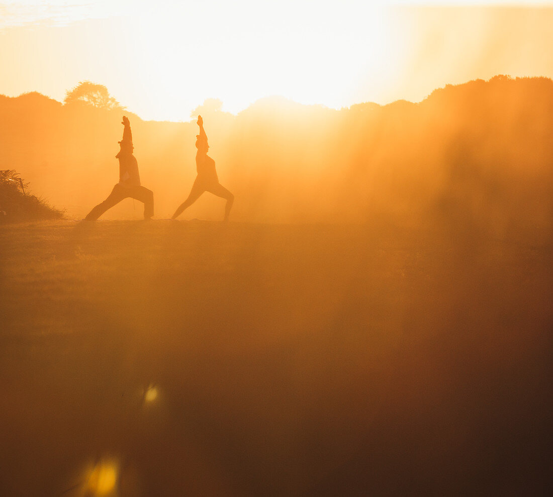 Zwei Frauen beim Yoga am Strand im Morgenlicht, Portugal