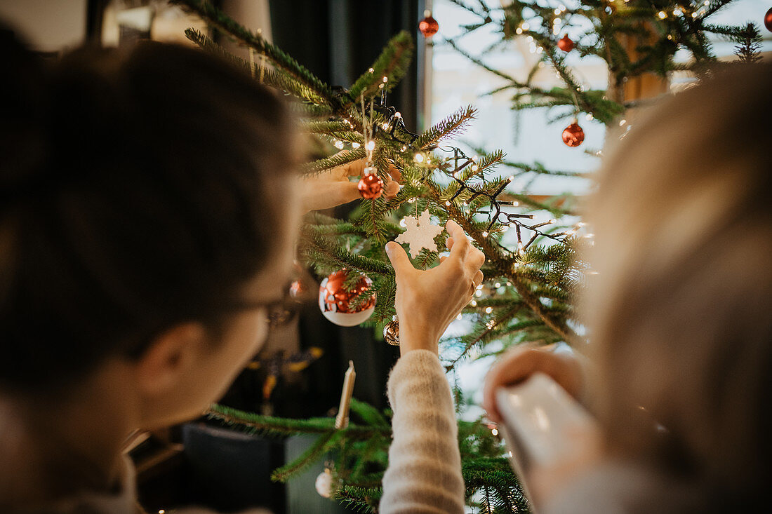 Mutter schmückt mit ihrem Sohn Christbaum