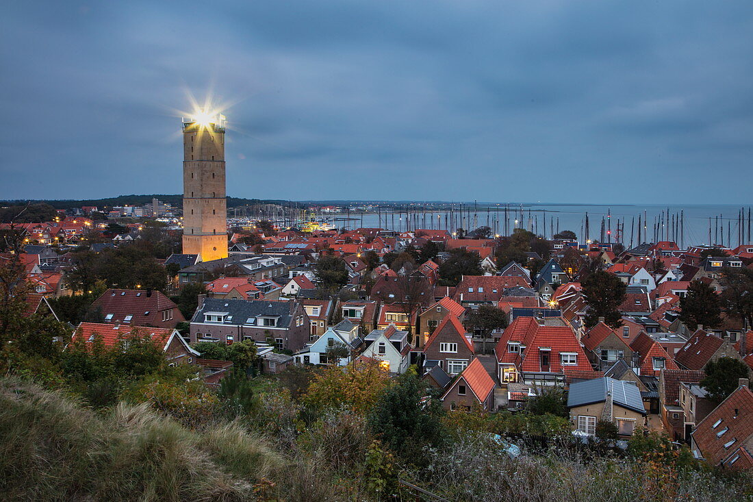 Terschelling Leuchtturm und Stadt mit Yachthafen in der Abenddämmerung vom Hügel aus gesehen, West Terschelling, Terschelling, Westfriesische Inseln, Friesland, Niederlande, Europa