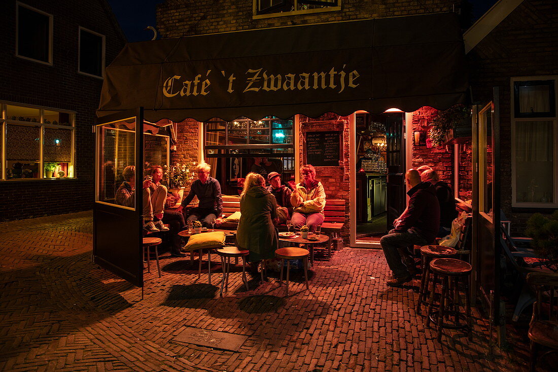 Menschen sitzen vor dem Café 't Zwaantje und genießen nachts Bier, West Terschelling, Terschelling, Westfriesische Inseln, Friesland, Niederlande, Europa