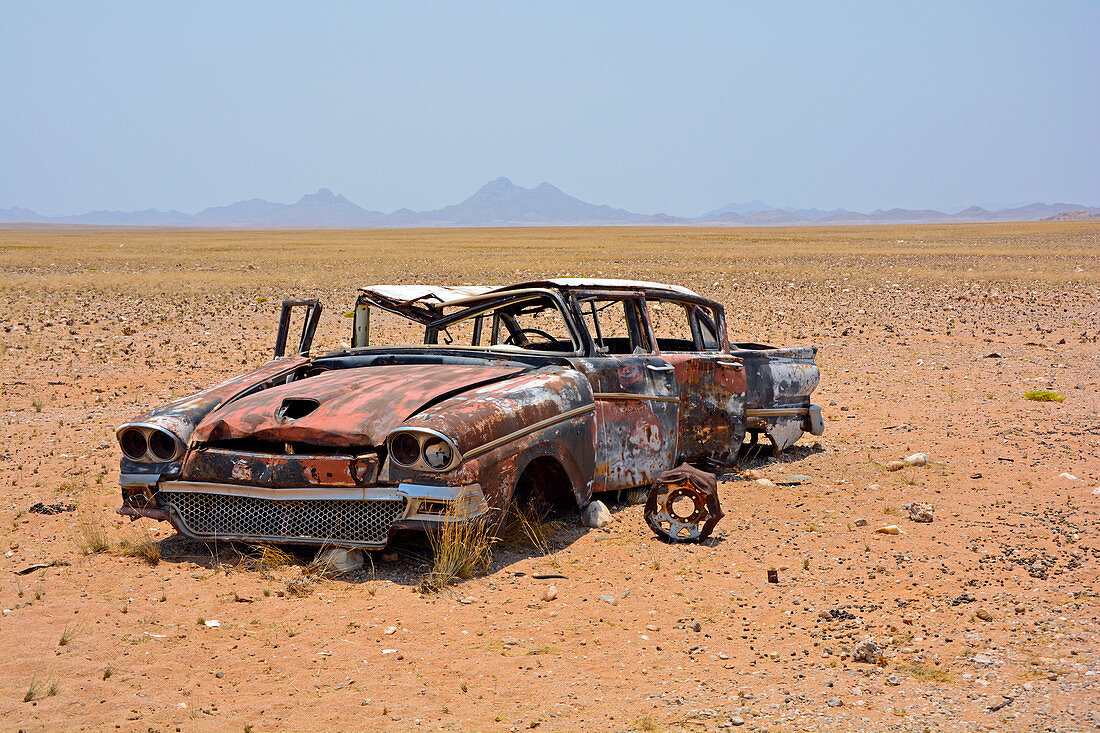 Angola; im südlichen Teil der Provinz Namibe; Wüste im Iona Nationalpark; Ende der Trockenzeit; Schotterebene und weitläufige Grasflächen; Wrack eines Oldtimers;