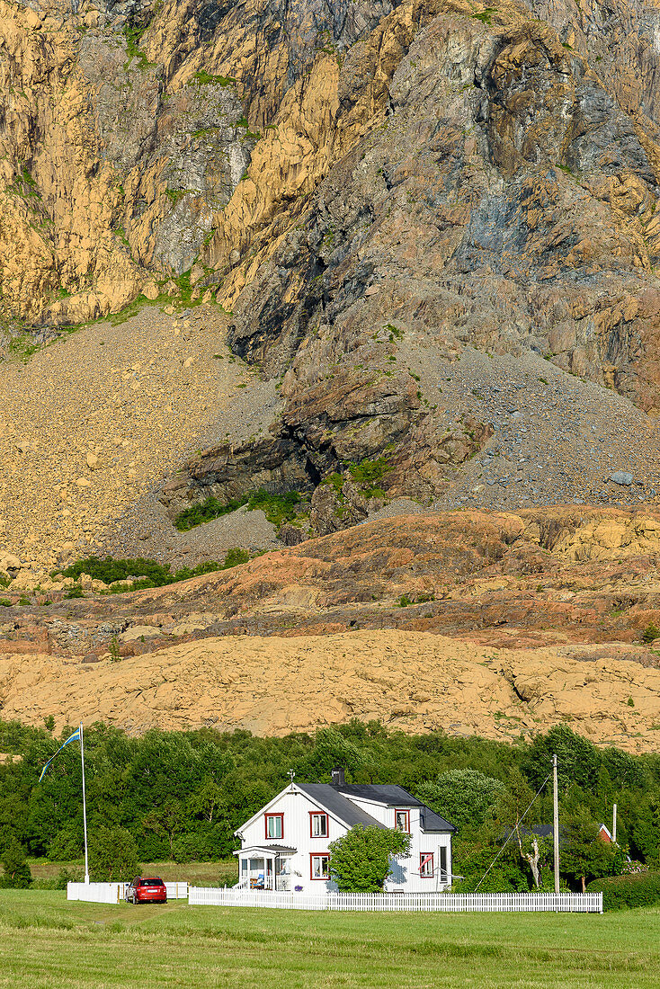 Haus vor Felswand mit Serpentinit und Olivinstein, Insel Leka, Norwegen