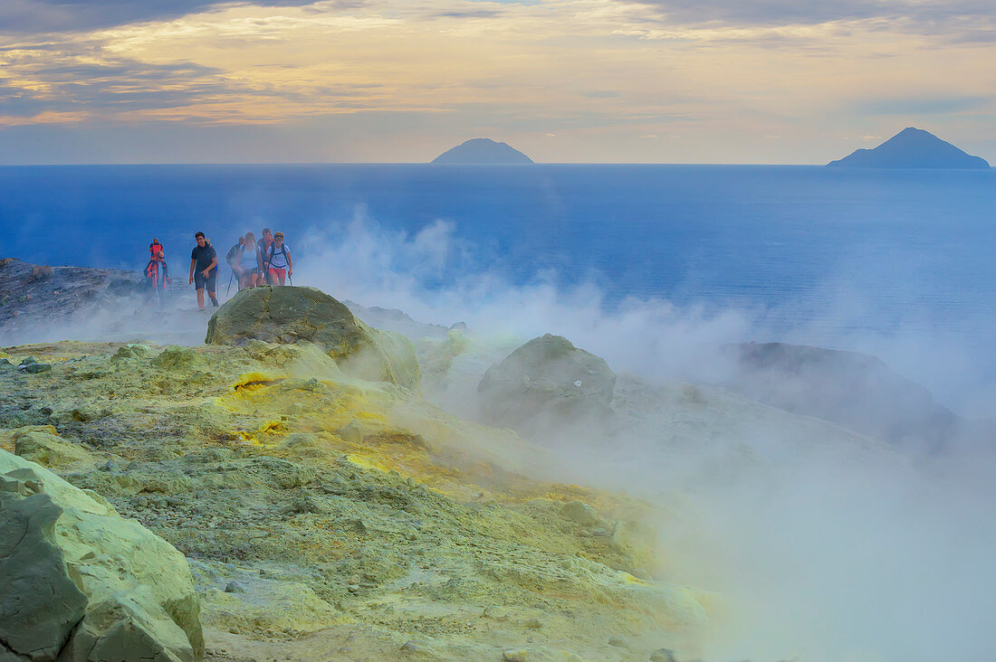 Hikers walking through fumaroles smoke on Gran Cratere rim, Vulcano Island, Aeolian Islands,  Sicily, Italy, 