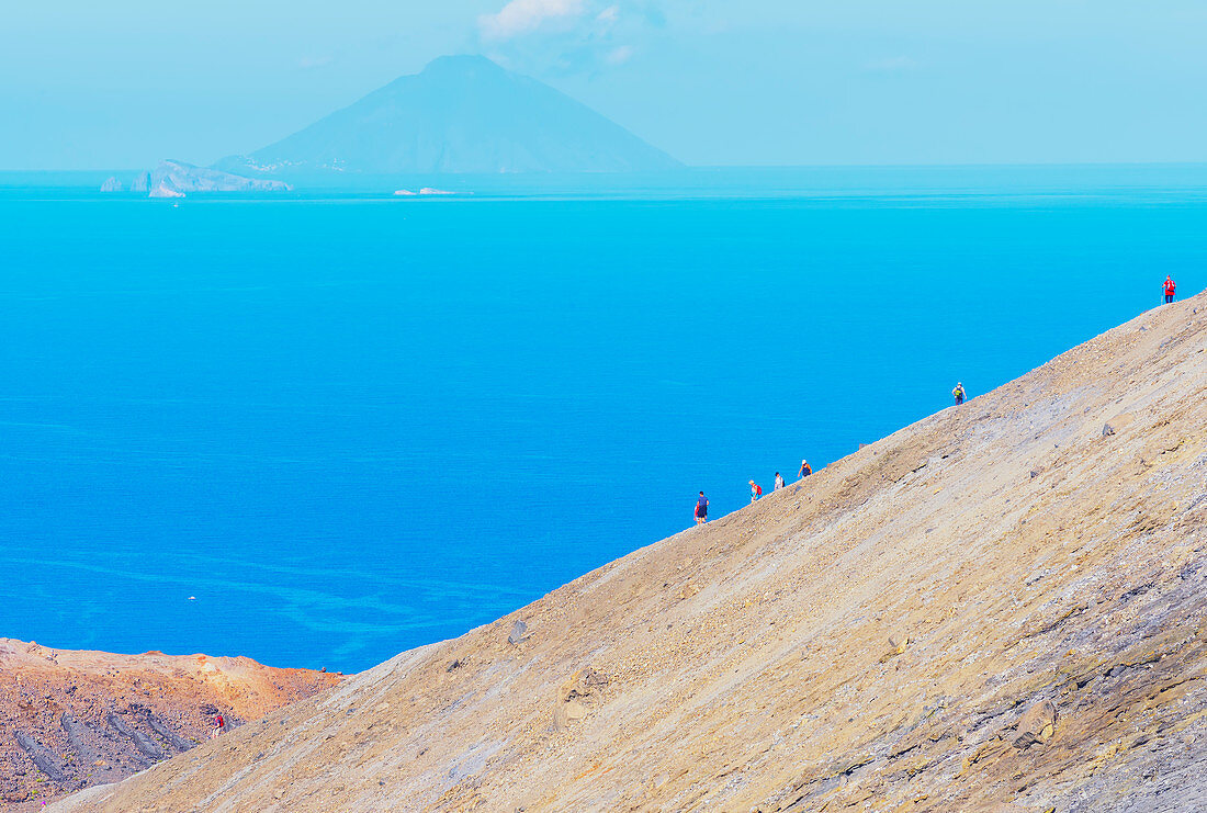 Hikers walking on Gran Crater rim, Vulcano Island, Aeolian Islands, Sicily, Italy