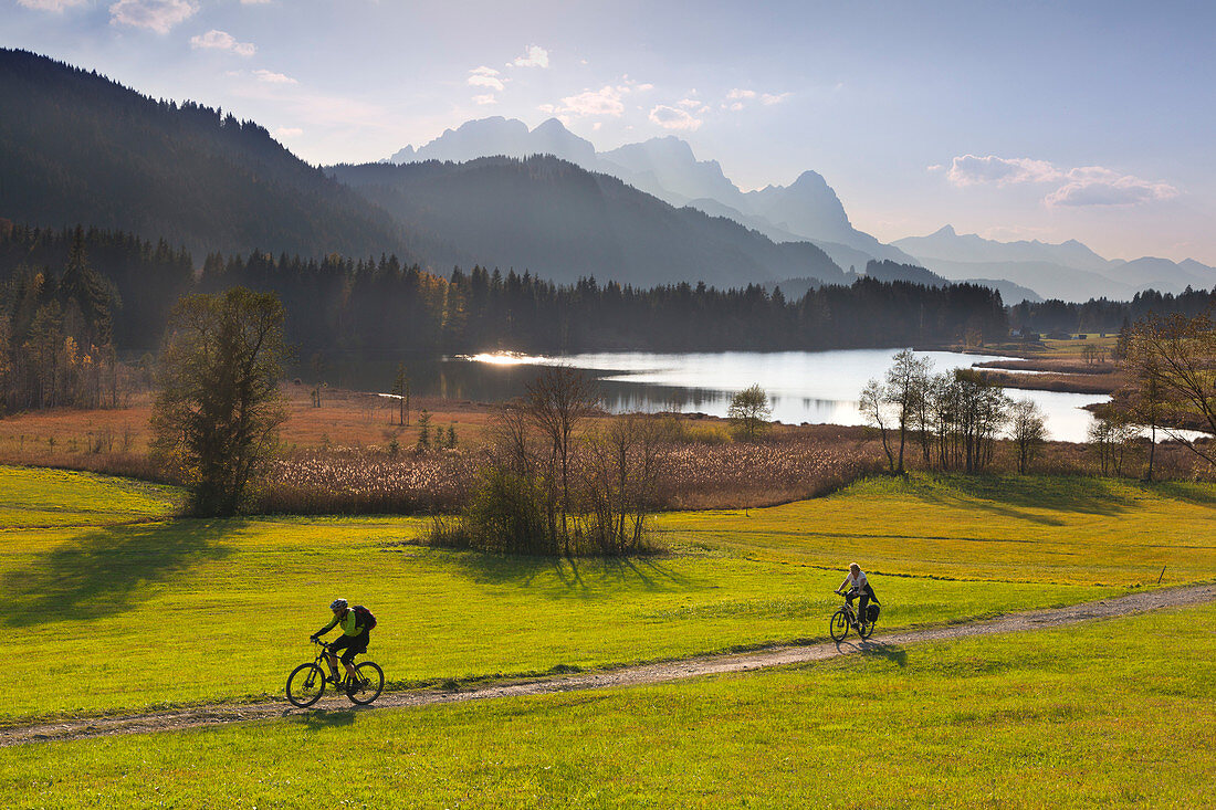 Cyclists, view over the Geroldsee to the Zugspitze massif with Alpspitze, Zugspitze and Waxenstein, Werdenfelser Land, Bavaria, Germany