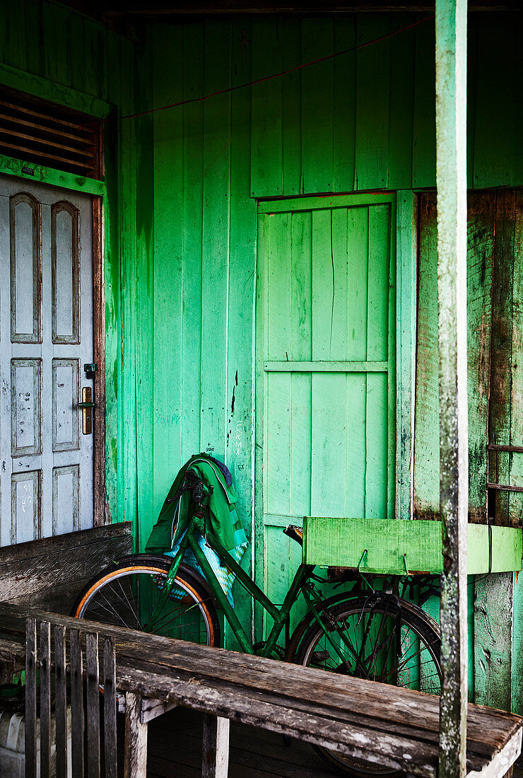 Ein grünes Fahrrad lehnt sich an ein grün gestrichenes Haus in Palangkaraya, Zentralkalimantan, Borneo, Indonesien