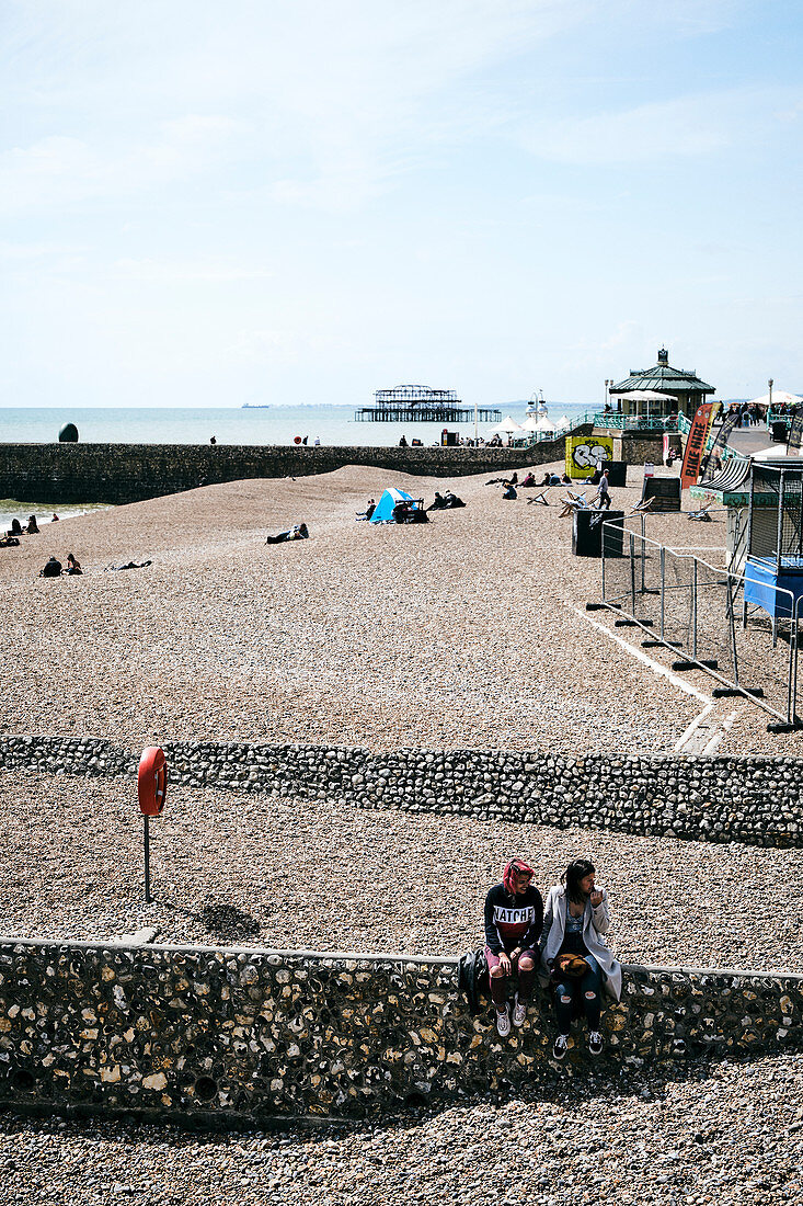 A view of Brighton Beach looking towards the burnt remains of West Pier, Brighton, East Sussex, UK.