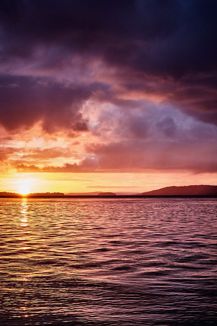 Sonnenuntergang in der Nelson Bay mit heranziehenden Gewitterwolken über dem Wasser