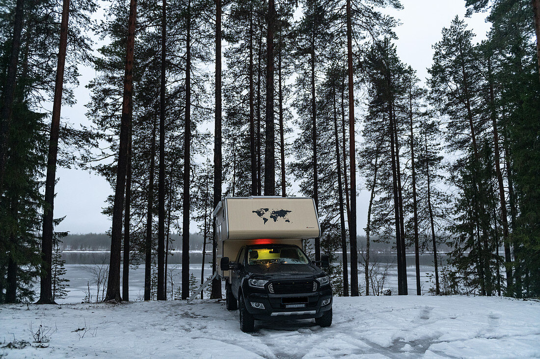 Ein Van parkt im tiefen Winter auf einem Stellplatz am Fluss, Östavall, Lappland, Schweden