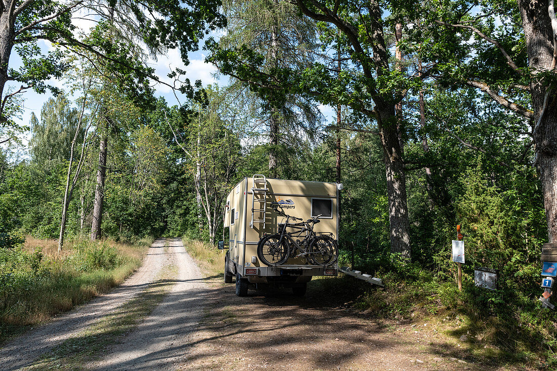 Campervan stands in the middle of the forest by the lake with bicycles, near Emmaboda, Småland, Sweden