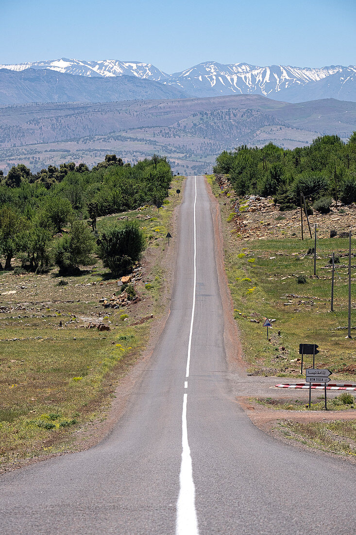 Lange geteerte Straße mit dem schneebedeckten Atlasgebirge im Hintergrund, Marokko, Nordafrika, Afrika