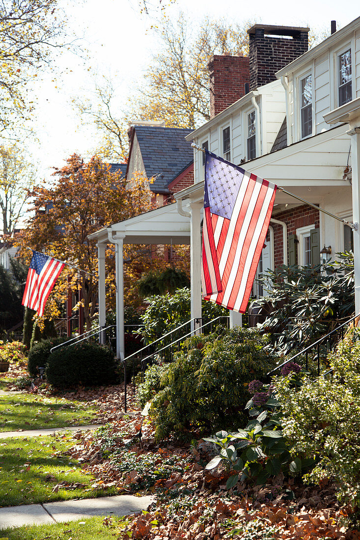 Amerikanische Flaggen hängen vor vorstädtischen Häusern