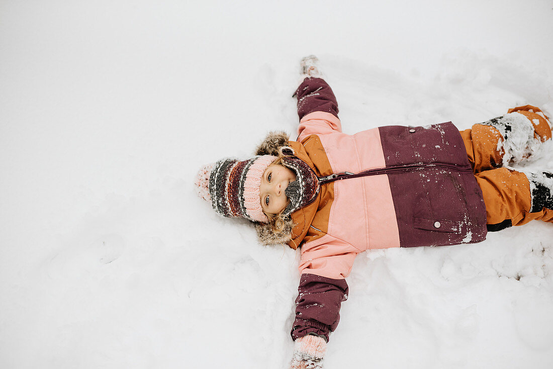Kanada, Ontario, Mädchen (2-3) macht Schneeengel