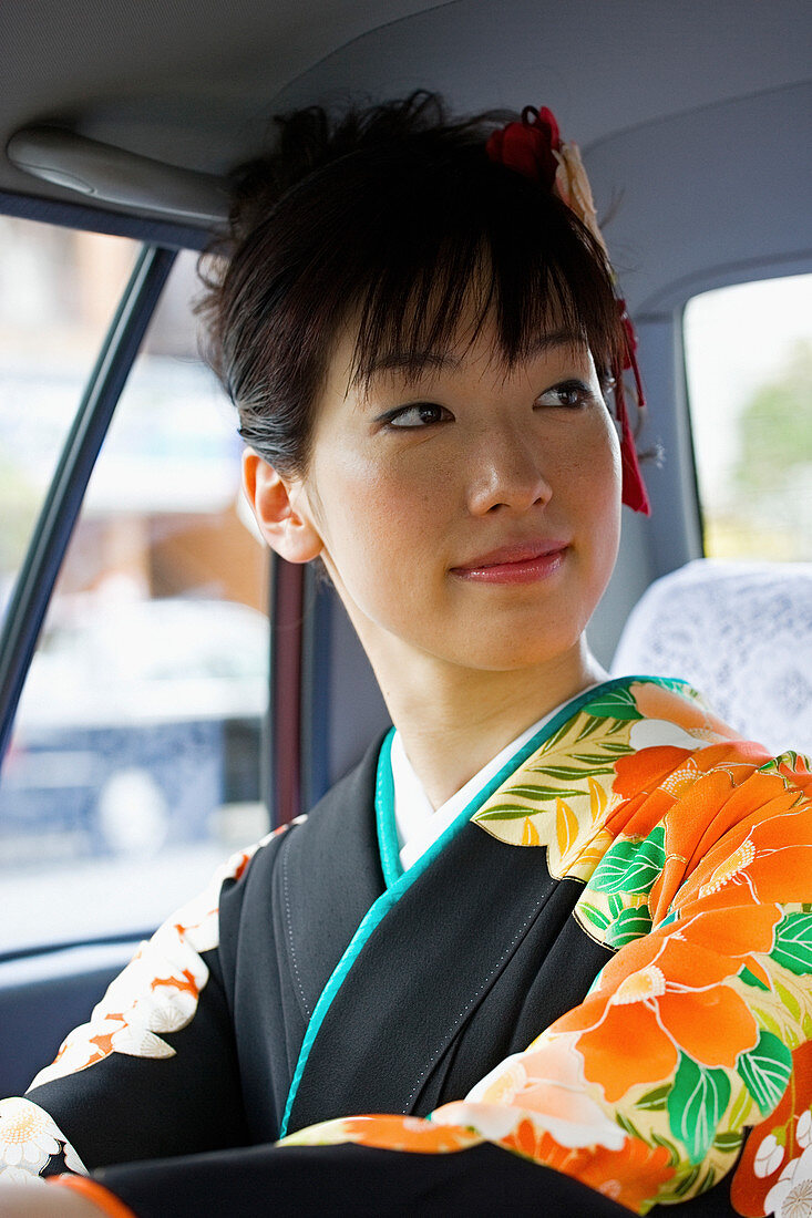 Schöne japanische Frau im Kimono auf dem Rücksitz des Taxis