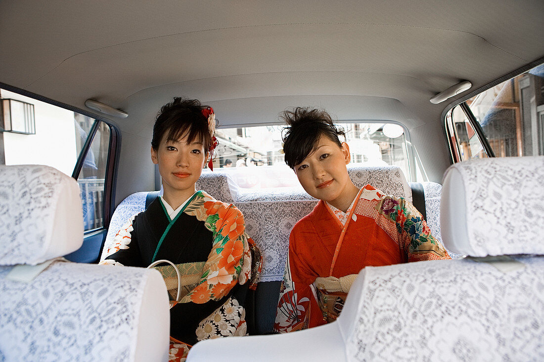 Porträt japanischer Frauen in Kimonos, die auf dem Rücksitz des Autos reiten
