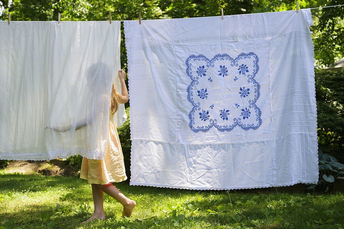 Girl (6-7) with laundry in backyard