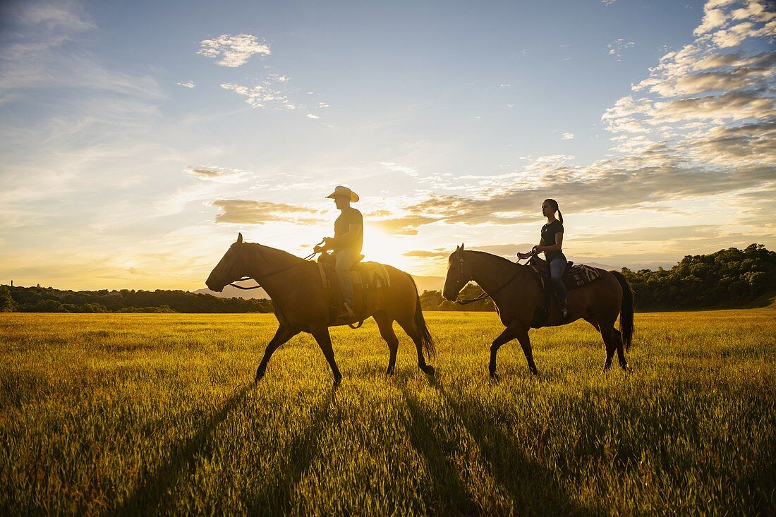 USA, Utah, Salem, Vater und Tochter (14-15 Jahre) Reitpferde bei Sonnenuntergang
