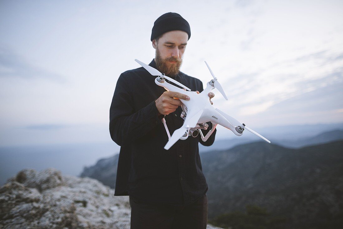 Italien, Ligurien, La Spezia, Mann am Berggipfel mit Drohne