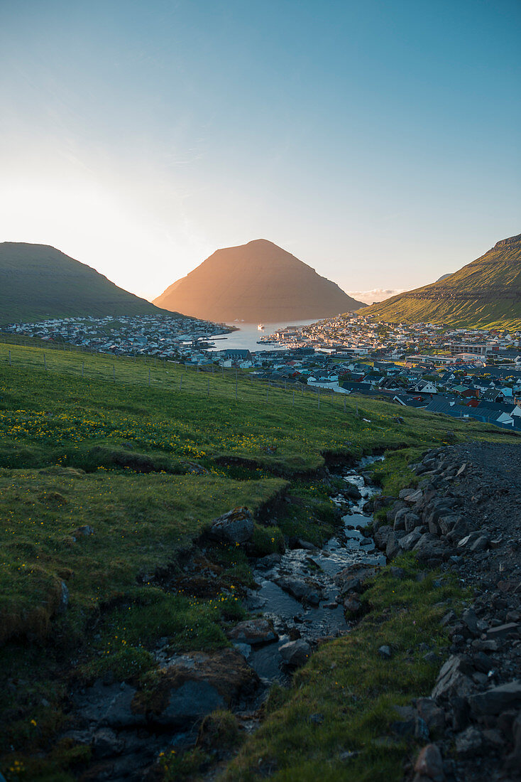 Dänemark, Färöer, Klaksvik, Landschaft mit Bergen und Dorf auf dem Seeweg im Morgengrauen