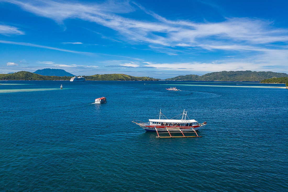 Luftaufnahme von traditionellem philippinischen Banca Auslegerkanu Ausflugsboot, einem Tenderboot und dem Kreuzfahrtschiff Silver Shadow vor Anker in der Ferne, Barangay I, Romblon, Romblon, Philippinen, Asien