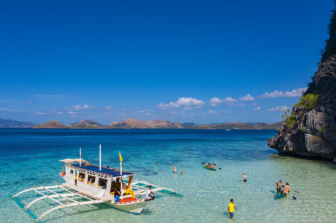 Luftaufnahme von traditionellem philippinisches Banca Auslegerkanu und Gäste, die Wasseraktivitäten am Strand 91 auf der Insel Coron genießen, Banuang Daan, Coron, Palawan, Philippinen, Asien
