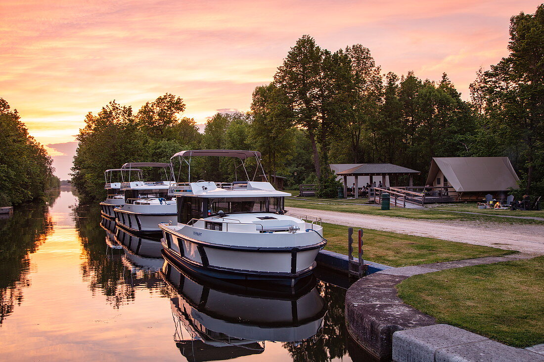 Drei Le Boat Horizon Hausboote angedockt an den Schleusen Beveridge Locks am Fluss Tay River mit Parks Canada Campingplatz bei Sonnenuntergang, nahe Lower Rideau Lake, Ontario, Kanada, Nordamerika