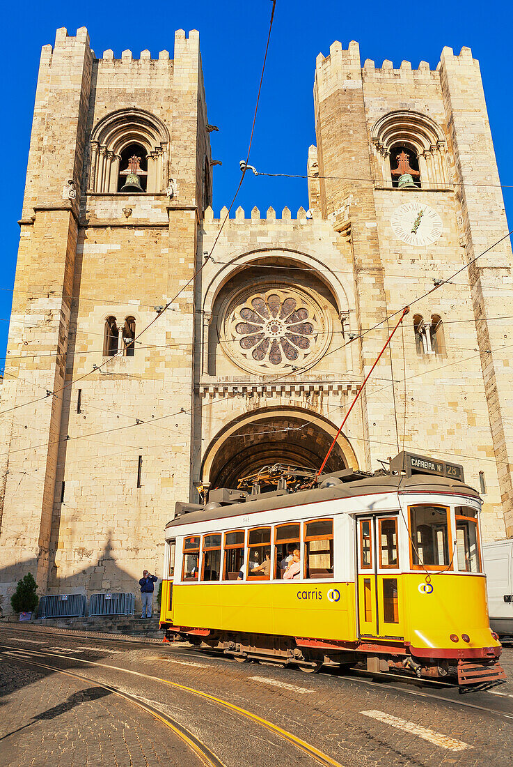 Electric tram passing Santa Maria Maior cathedral, Lisbon, Portugal