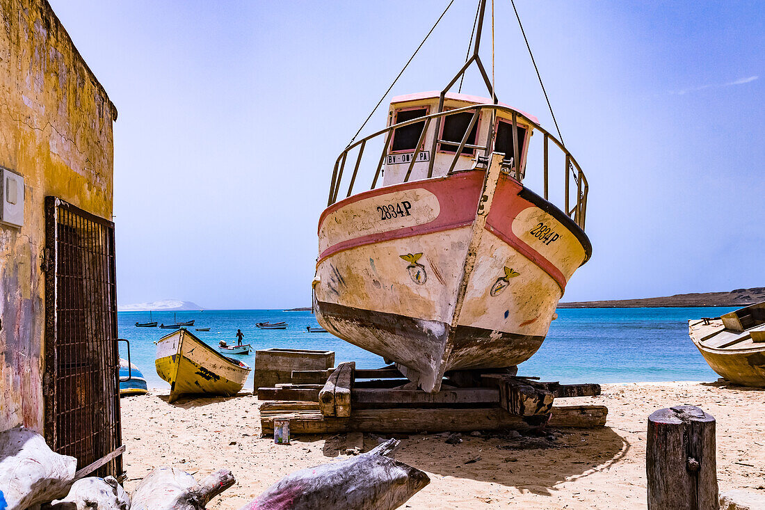 Direkt am Meer der Insel Kapverden Insel Boa Vista ist ein Boot auf einfachen Balken hochgebockt, Afrika