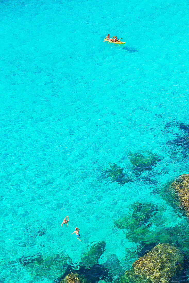 People canoeing and swimming at Cala Mitjana, Minorca, Balearic Islands. Spain