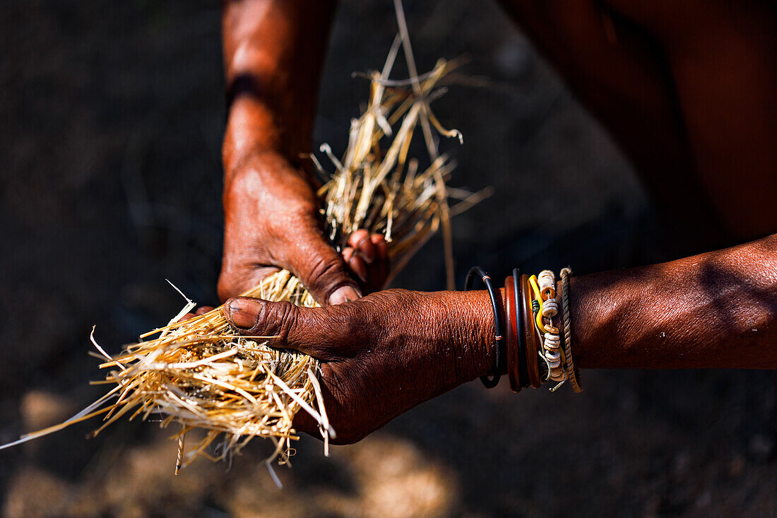 An old man with distinctive hands collects straw in Namibia, Africa