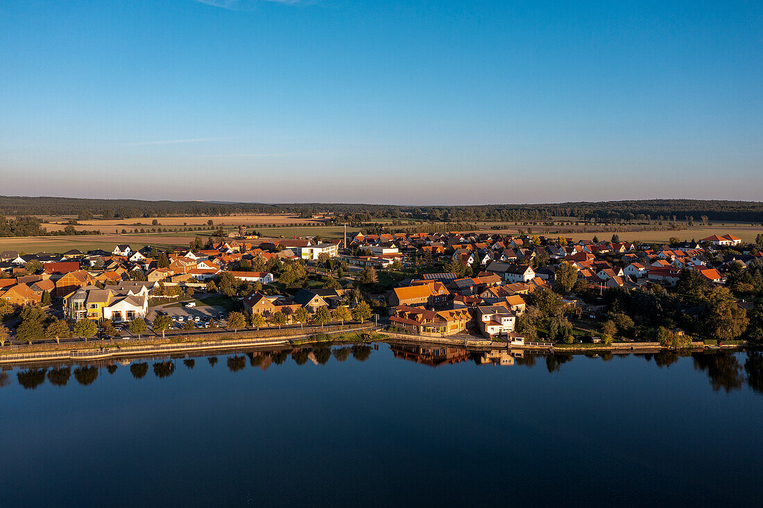 Deciduous trees and houses are reflected in the castle pond, Flechtingen, Saxony-Anhalt, Germany