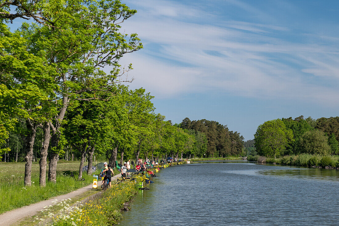 Numerous anglers sit on the Göta Canal, near Norrqvarn, Västra Götaland, Sweden