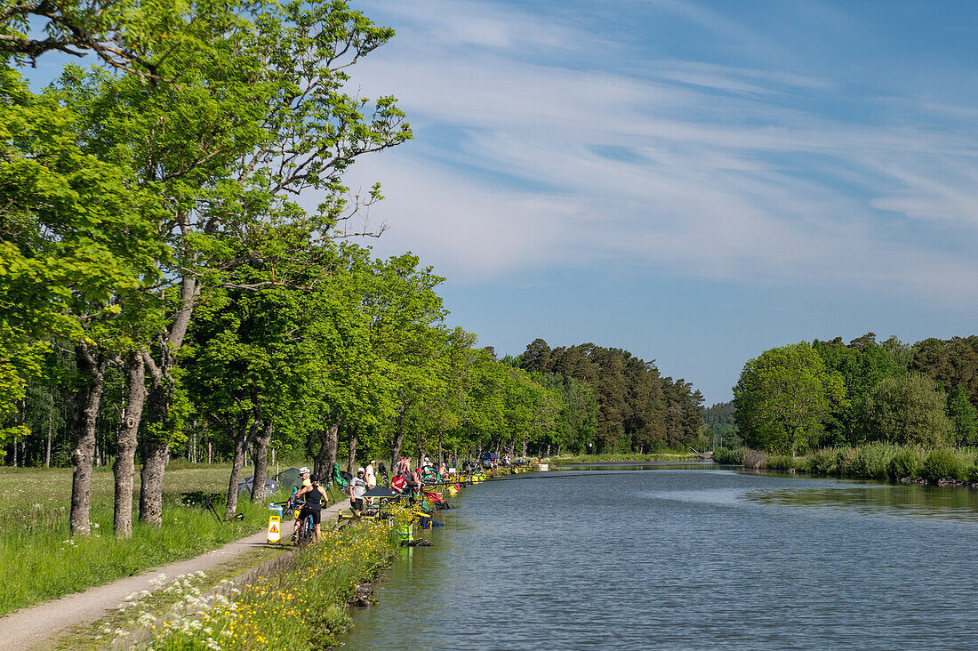 Zahlreiche Angler sitzen am Götakanal, bei Norrqvarn, Västra Götaland, Schweden