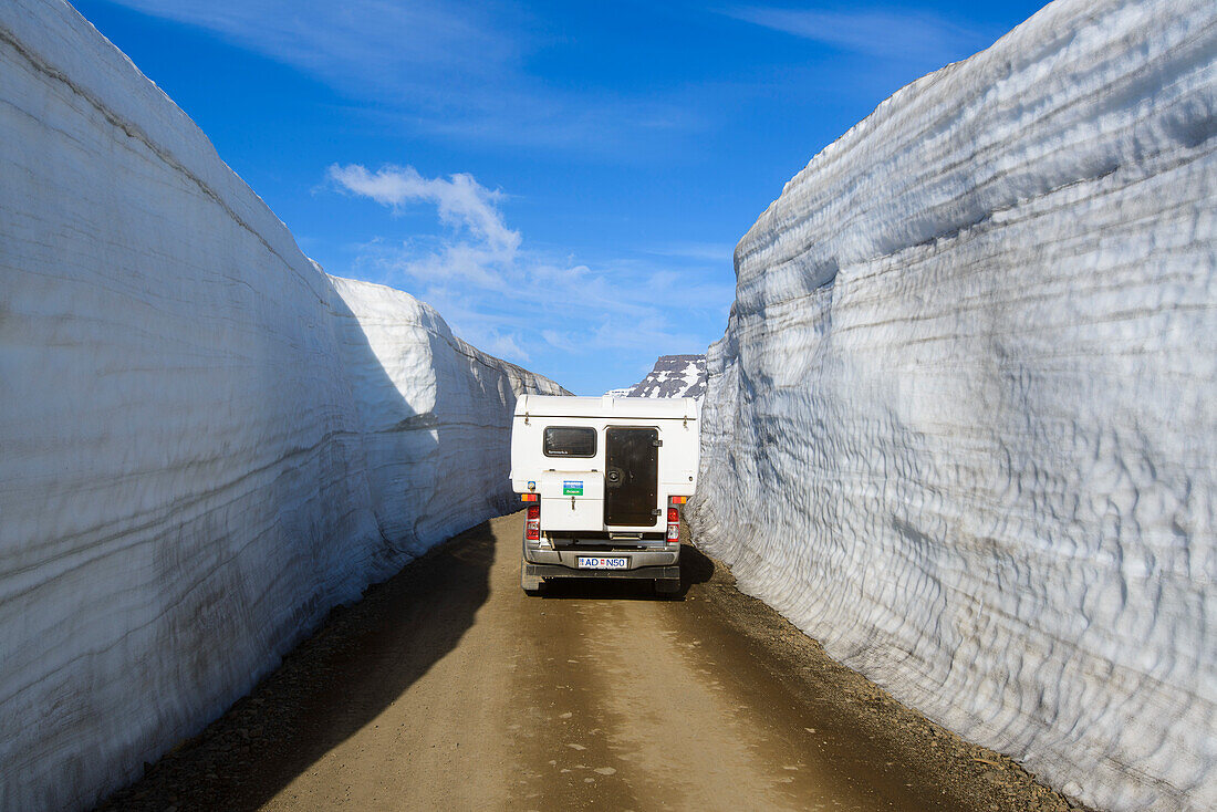 Hohe Schneewände an einem gefrästen Pass an den Ostfjorden Islands