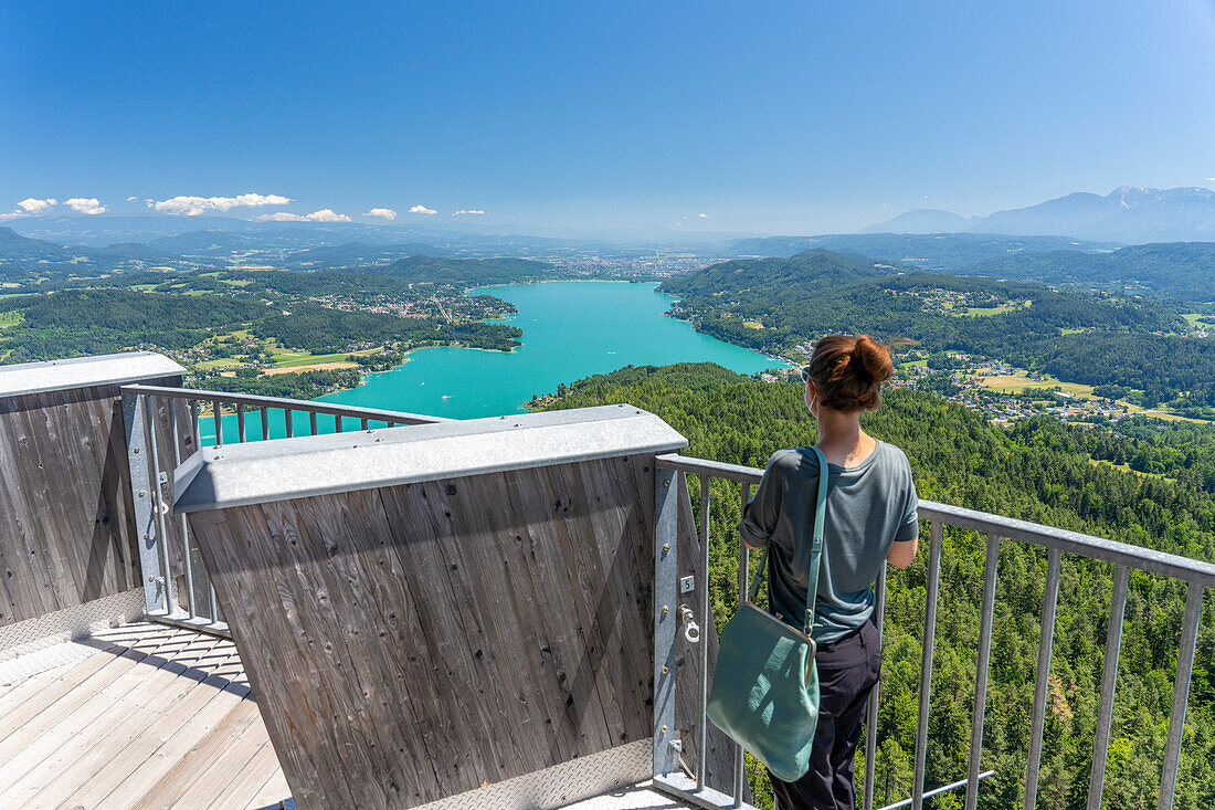 Eine Frau schaut vom Aussichtsturm Pyramidenkogel auf den Wörthersee, Kärnten, Österreich