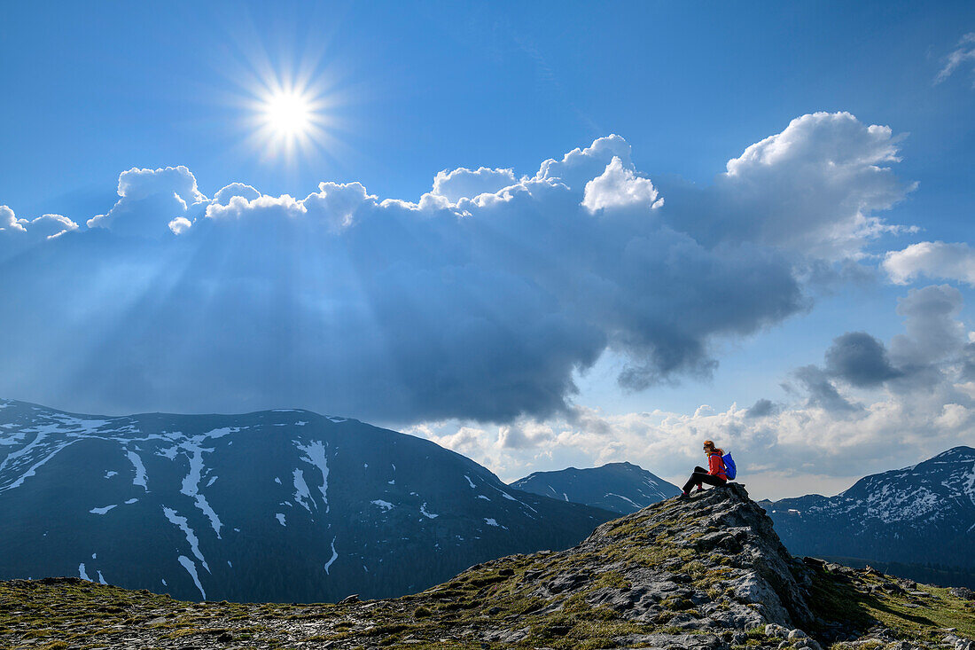 Frau beim Wandern sitzt auf Felsen, Wolkenstimmung im Hintergrund, Königstuhl, Nockberge, Nockberge-Trail, UNESCO Biosphärenpark Nockberge, Gurktaler Alpen, Kärnten, Österreich