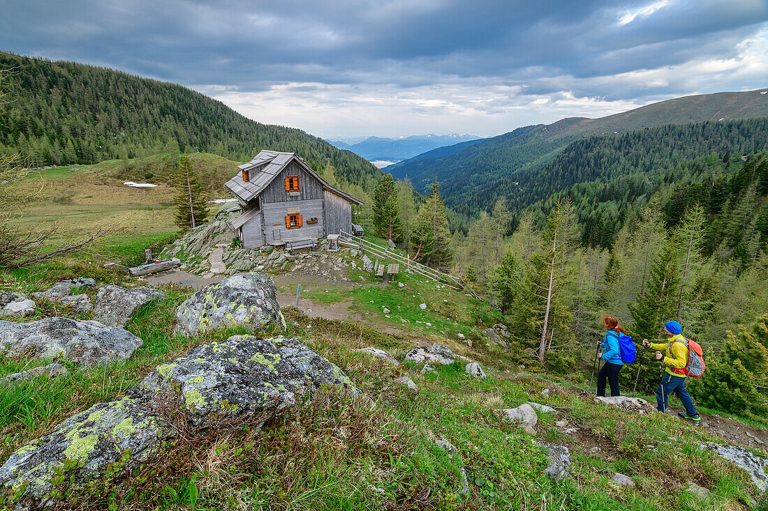 Man and woman hike towards alpine pastures, St. Oswalder Bockhütte, Nockberge, Nockberge-Trail, UNESCO Nockberge Biosphere Park, Gurktal Alps, Carinthia, Austria